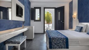 A modern hotel room with a bed, a bench, a desk, and a view of the outdoors. - Rivari Apartments (Santorini)