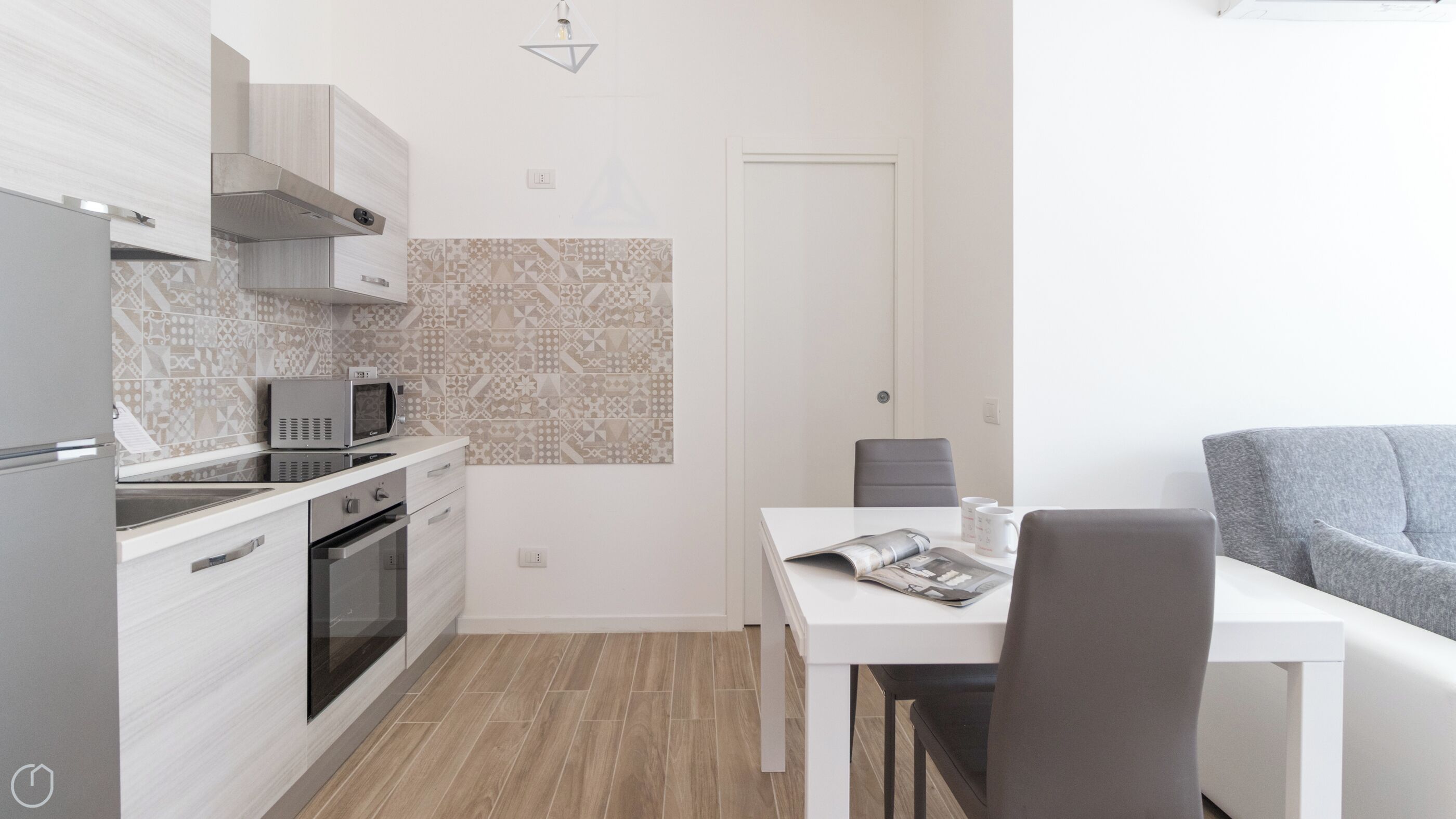 Cocina compacta con microondas, horno y comedor con mesa y sillas.