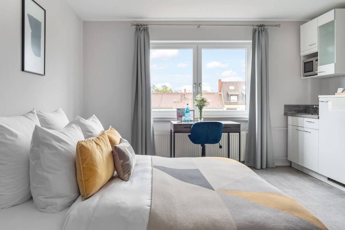 Une chambre moderne avec un grand lit, un bureau et un coin cuisine.