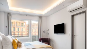 Una habitación de hotel moderna con una cama, un televisor de pantalla plana, una silla y una puerta.