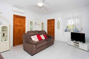 A living room with a brown sofa, a television, and a ceiling fan. - CH La Pinada Pueblo Bravo (Ciudad Quesada) (Ciudad Quesada)