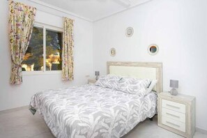 A bedroom with a bed, curtains, a nightstand, and a window. - CH La Pinada Pueblo Bravo (Ciudad Quesada) (Ciudad Quesada)