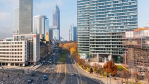 A cityscape with modern high-rise buildings, a wide road, and a pedestrian walkway. - Numa Frankfurt Blau (Frankfurt)