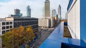 A cityscape with modern buildings, a clear sky, and a tree with autumn leaves. - Numa Frankfurt Blau (Frankfurt)