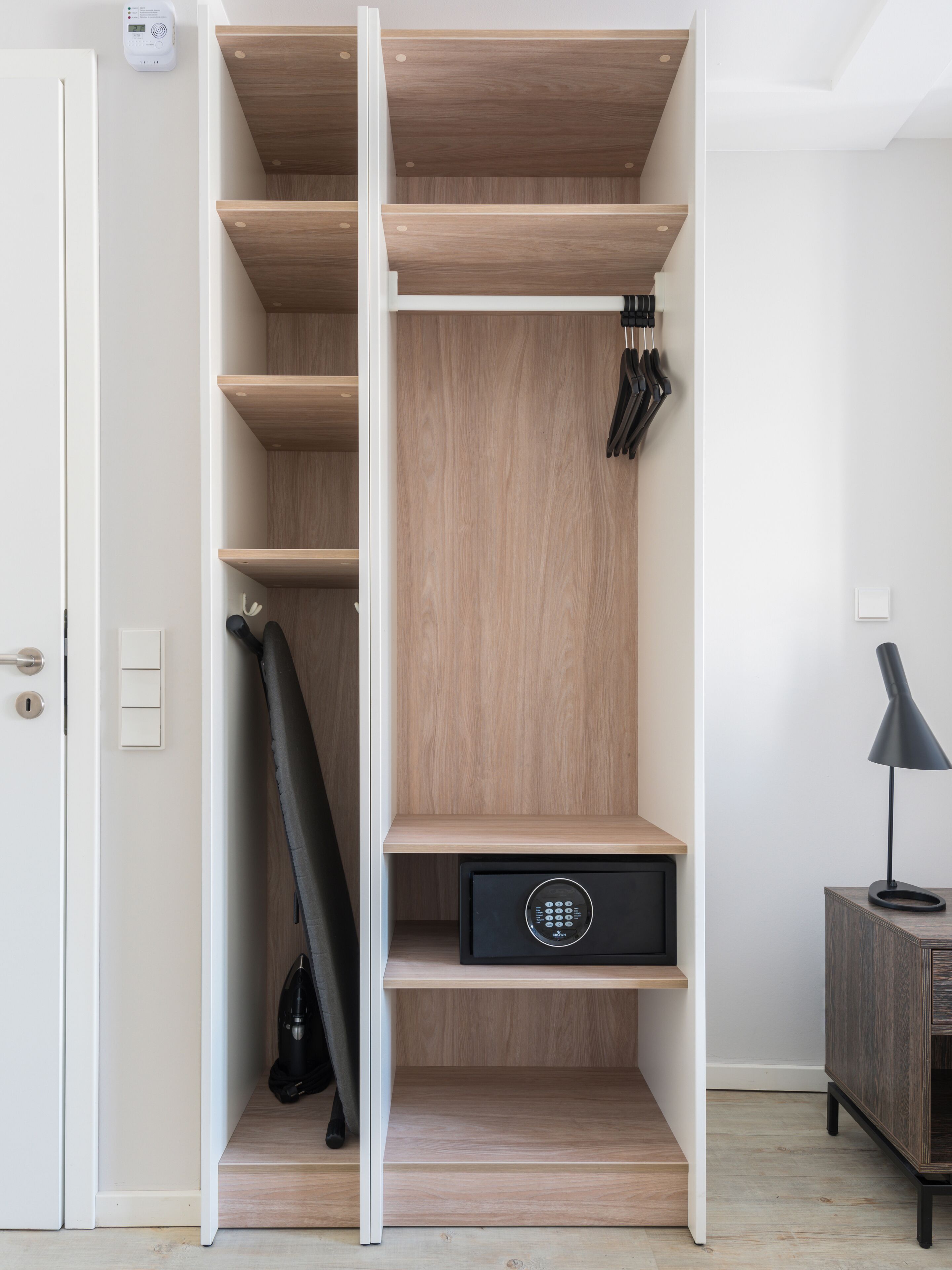 Una habitación moderna y minimalista con un armario empotrado que incluye varias estanterías y un zapatero.