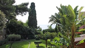 Un jardin bien entretenu, agrémenté de diverses plantes, d’un chemin de pierre et offrant une vue sur la mer.