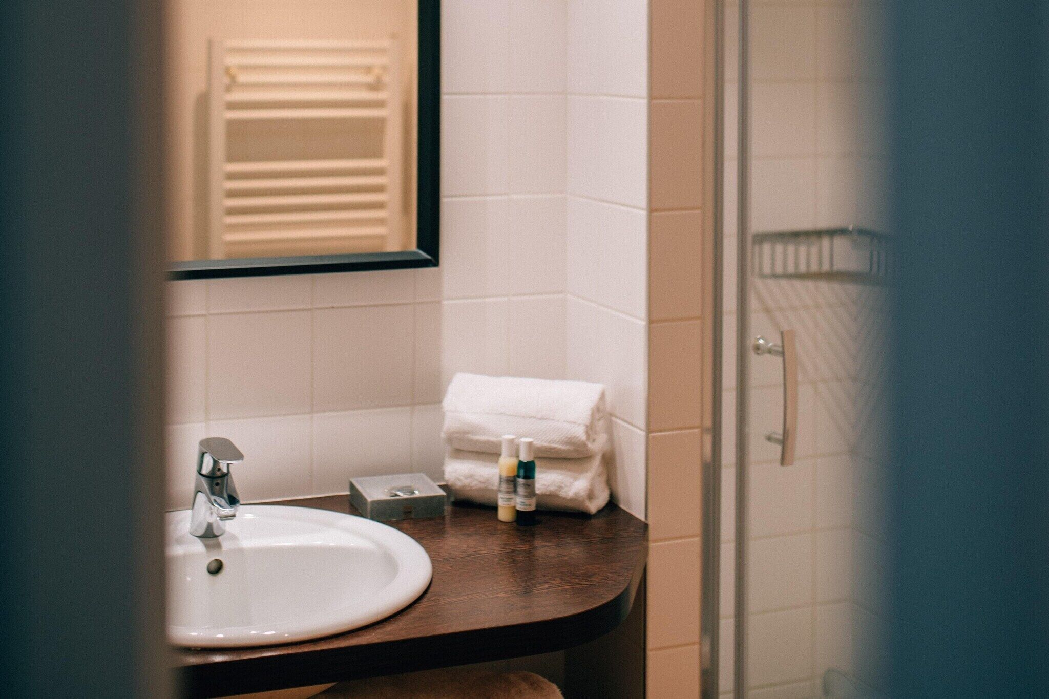 A bathroom with a white sink, a mirror, and a towel rack.