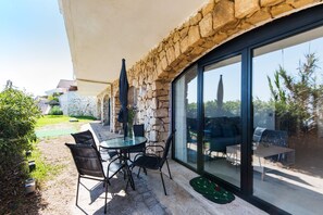A patio with stone walls, a glass door, and outdoor furniture.