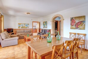 Un vaste espace de vie comprenant une table à manger en bois, de nombreux sièges et des œuvres d’art accrochées aux murs.