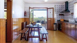 A kitchen with wooden cabinets, a dining area with a table and benches, and a view to an outdoor patio. - Villa Luis Vives with Mountain View, Wi-Fi, Garden, Balcony, Terraces & Pool (Port de Pollença)