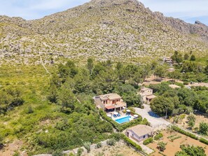 Una proprietà collinare con piscina, diversi edifici e vegetazione circostante.