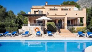 A two-story building with a swimming pool, blue lounge chairs, and a lifebuoy. - Villa Luis Vives with Mountain View, Wi-Fi, Garden, Balcony, Terraces & Pool (Port de Pollença)