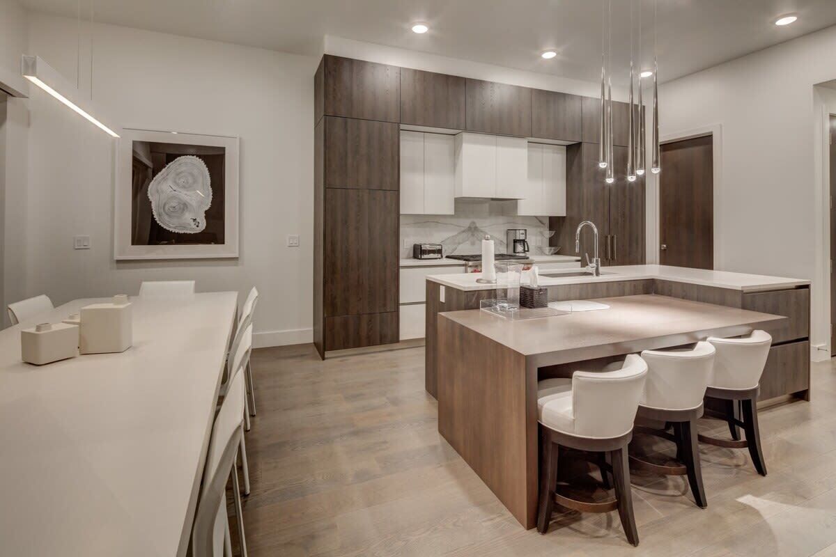 Una cocina moderna con una isla central, armarios de madera oscura y encimera blanca.