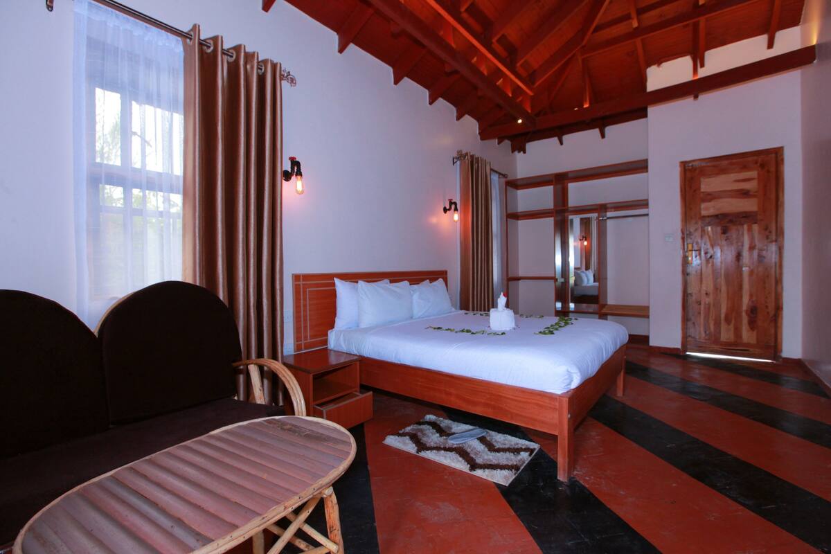 A hotel room with a bed, a chair, a table, and a wooden door.