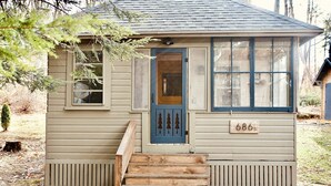 A small, single-story house with a blue door, a number '686' on the front, and a wooden staircase leading to the entrance. - Woodhaven Hideaway on Woods Pond.. (Bridgton)