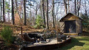 A rustic cabin with a fire pit, seating area, and a small shed. - Woodhaven Hideaway on Woods Pond.. (Bridgton)
