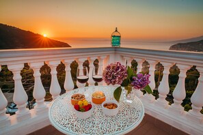 Een balkon met een gedekte tafel, met uitzicht op een schilderachtig zonsondergang.