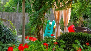 Un jardín con cerca de madera, un banco y un parque infantil.