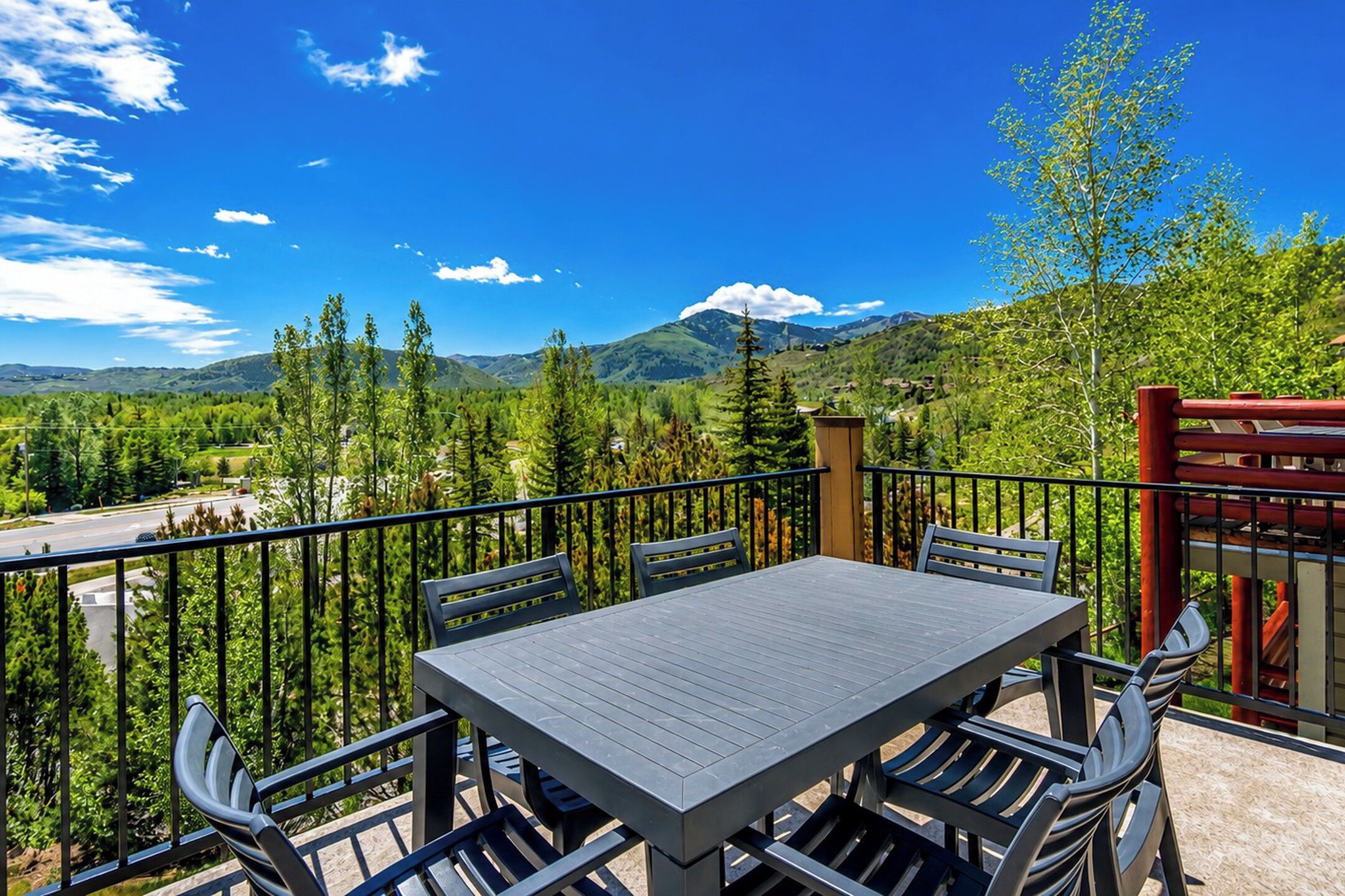 A balcony with a table and chairs, overlooking a mountainous landscape.