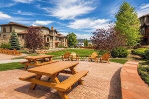 A patio area with picnic tables and Adirondack chairs, surrounded by stone walls and greenery. - Hot Tub, 2 Mi to Cabriolet Lift: Family Mtn Escape (Park City)