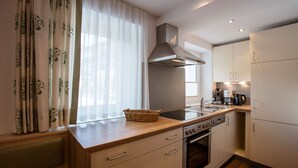 Une cuisine moderne dotée d’un plan de travail en bois, d’appareils électroménagers en acier inoxydable et d’une fenêtre ornée de rideaux légers.