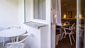 Ein Zimmer mit einer Schiebetür aus Glas, die zu einem Essbereich mit Holztischen und einer Tischplatte führt.