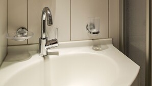 Ein weißes Waschbecken mit chromfarbenem Wasserhahn und Seifenschale.