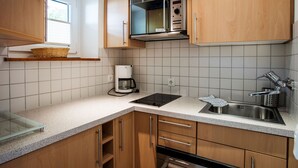 Eine moderne Küche mit Holzschränken, einer Edelstahl-Spüle, einer Mikrowelle und einer Kaffeemaschine.