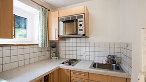 Une cuisine avec des meubles en bois, un évier en acier inoxydable, un four à micro-ondes et une cuisinière à gaz.