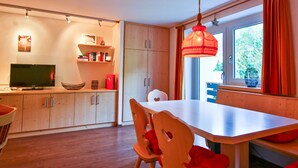 A modern kitchen with wooden cabinets, a dining table, and a TV.