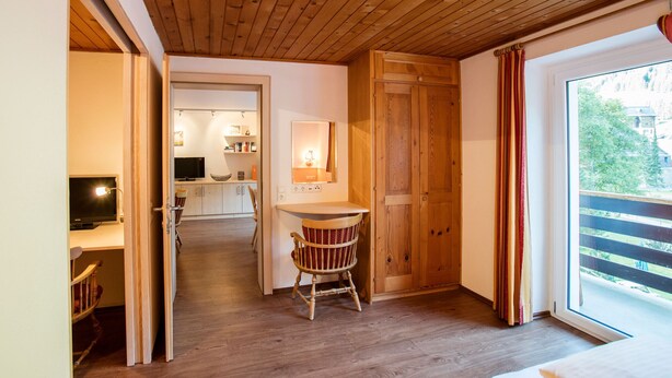 A wooden-paneled room with a dining area, a chair, and a view of the outdoors.