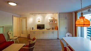 A compact living space with a dining area, kitchen, and a large window.