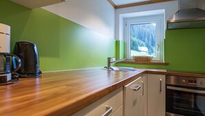 Una cucina con piano di lavoro in legno, una macchina da caffè, un forno in acciaio inossidabile e una finestra vista alberi.