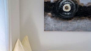 Une pièce avec un lit, un oreiller et un tableau représentant un pneu accroché au mur.