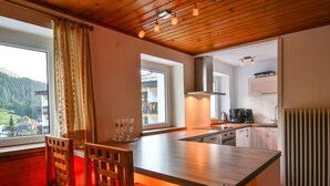 Une cuisine moderne avec un plancher en bois, un grand îlot central et une vue sur un paysage montagneux.