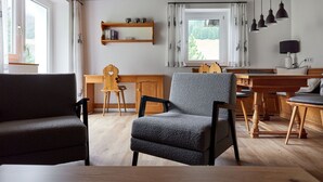 A modern living room with a wooden ceiling, a dining area with a wooden table and chairs, and a kitchen area with a stove and cabinets. - 5304 Diane "304" (Gargellen)