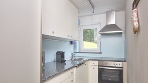 A compact kitchen with white cabinets, a built-in oven, and a window above the sink. - 5304 Diane "304" (Gargellen)