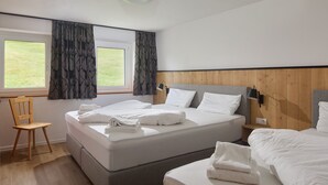 A hotel room with two beds, a wooden headboard, a desk with a chair, and a window with curtains. - 5304 Diane "304" (Gargellen)