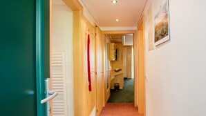 Ein schmaler Flur mit Holztüren, einem Heizkörper und einem gerahmten Bild an der Wand.