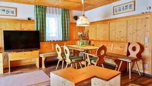 Une pièce aux murs lambrés, avec un téléviseur, des meubles en bois et une table à manger.