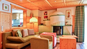 Un salon chaleureux avec un plafond en bois, un ensemble de canapés, une cheminée et une grande fenêtre.
