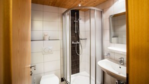 Un baño moderno con ducha de vidrio, lavabo blanco y retrete.