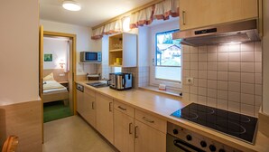 Una cocina compacta con estufa, microondas y un lavamanos pequeño.