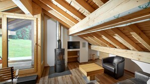 Een knus loft-appartement met een houten plafond, een open haard, een bank en een televisie.