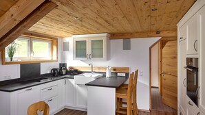 Een moderne keuken met witte kasten, een zwart aanrecht en houten vloeren.
