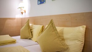 A hotel room with a bed, pillows, and artwork on the wall.