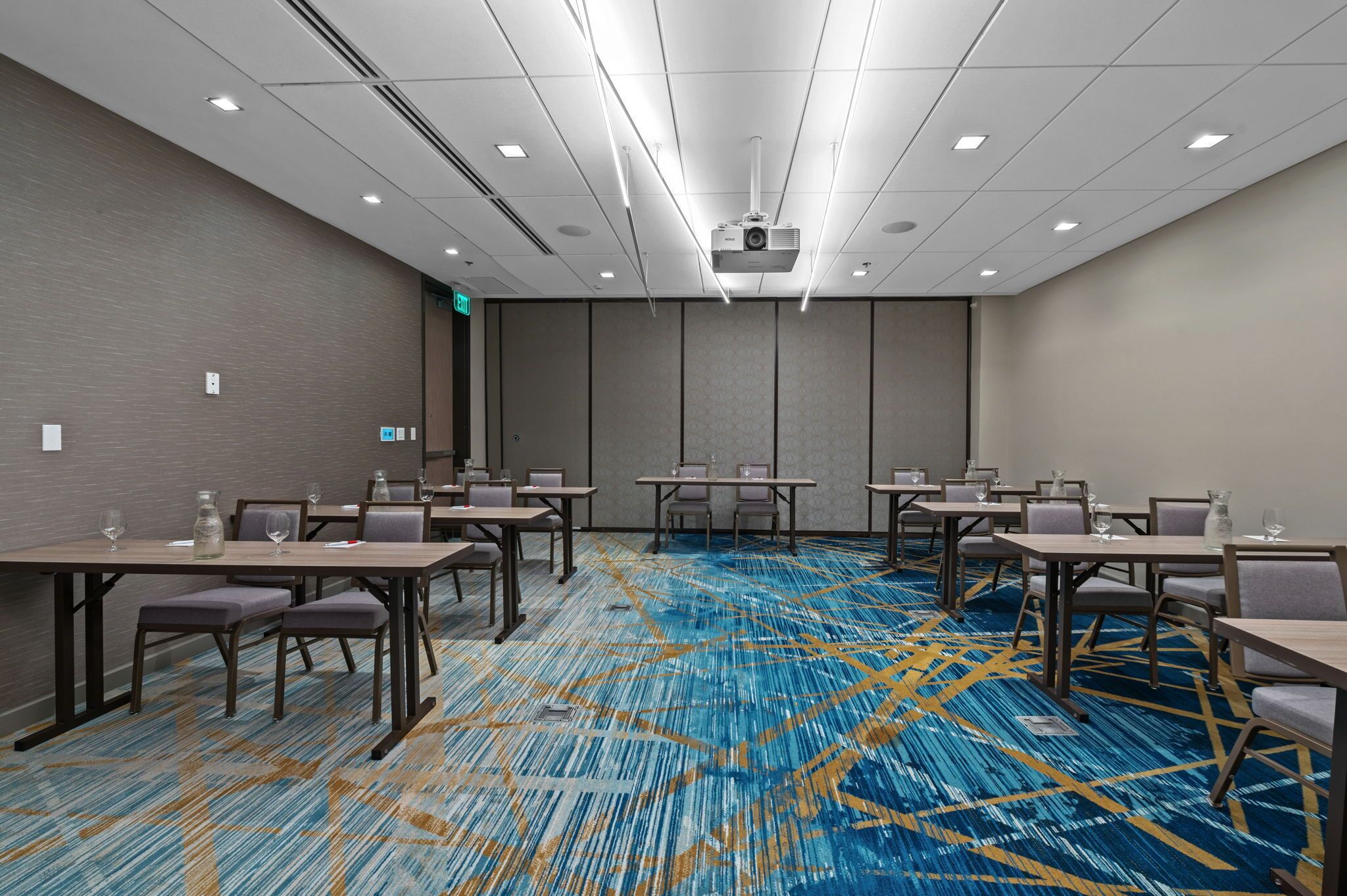 A conference room with a patterned carpet, multiple tables, and chairs.