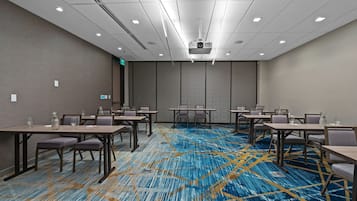A conference room with a patterned carpet, multiple tables, and chairs.