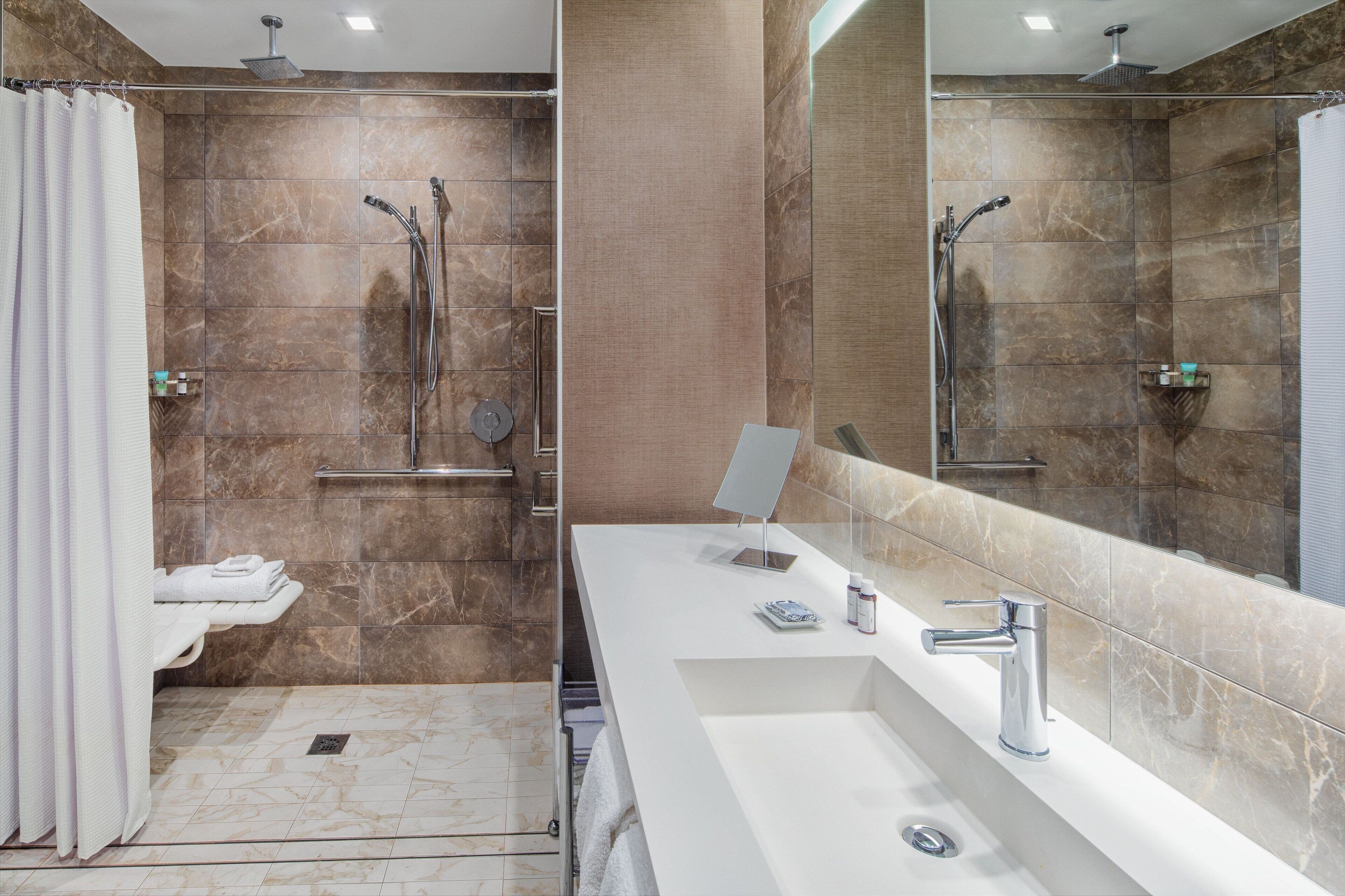 A modern bathroom with a shower, a sink, and a large mirror.