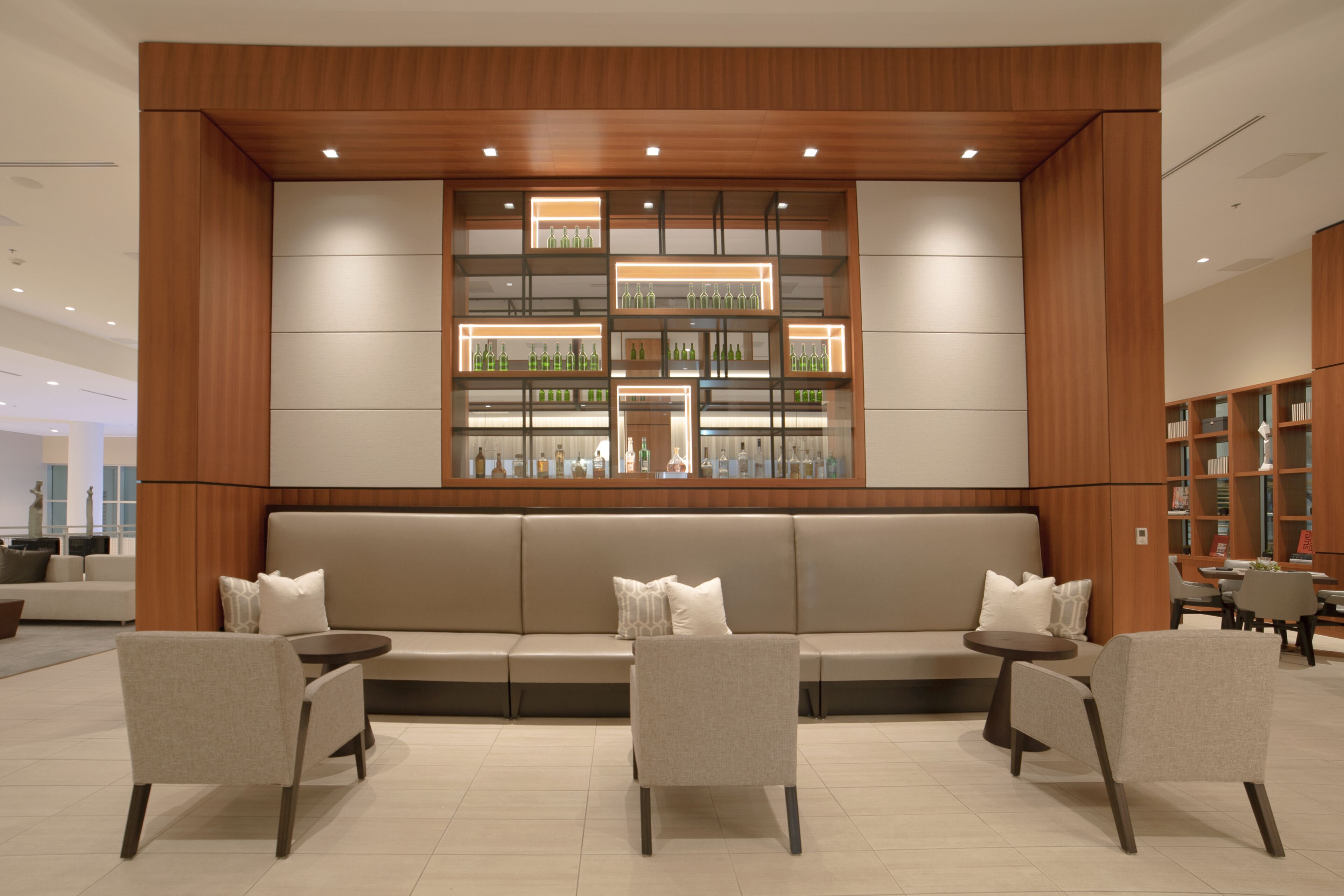 A modern lounge area with a sofa, chairs, and a display of bottles.